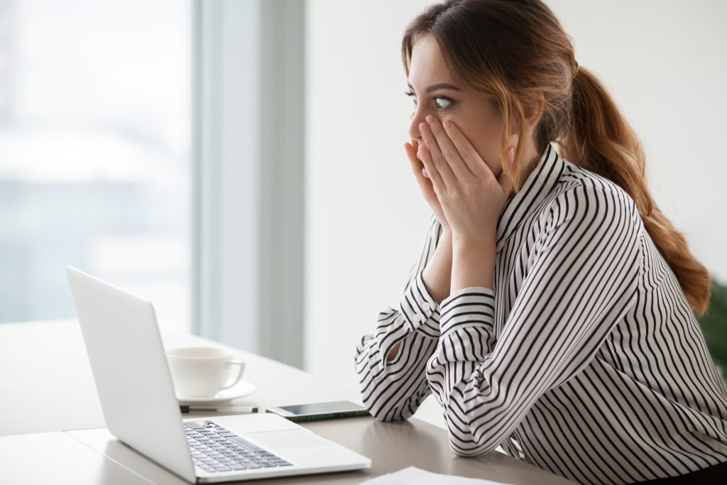 Shocked woman worker looking at laptop screen surprised with bad or unexpected online news, amazed businesswoman feel despair rounding eyes witnessing company bankruptcy or market failure