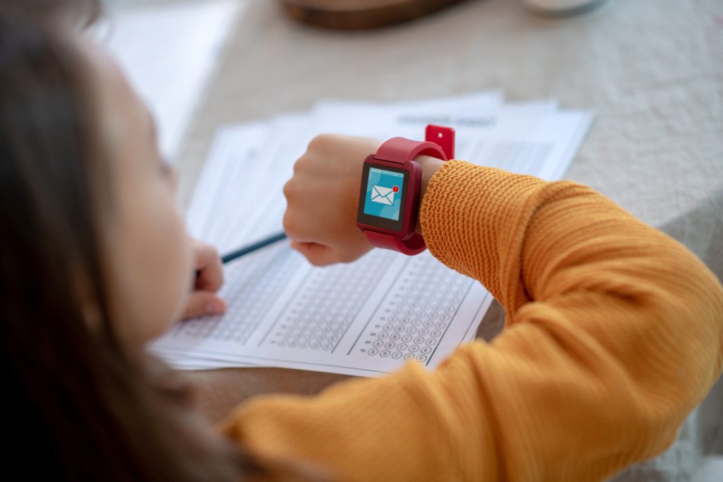Nice watch. Girl in orange shirt wearing smartwatch on red watchband