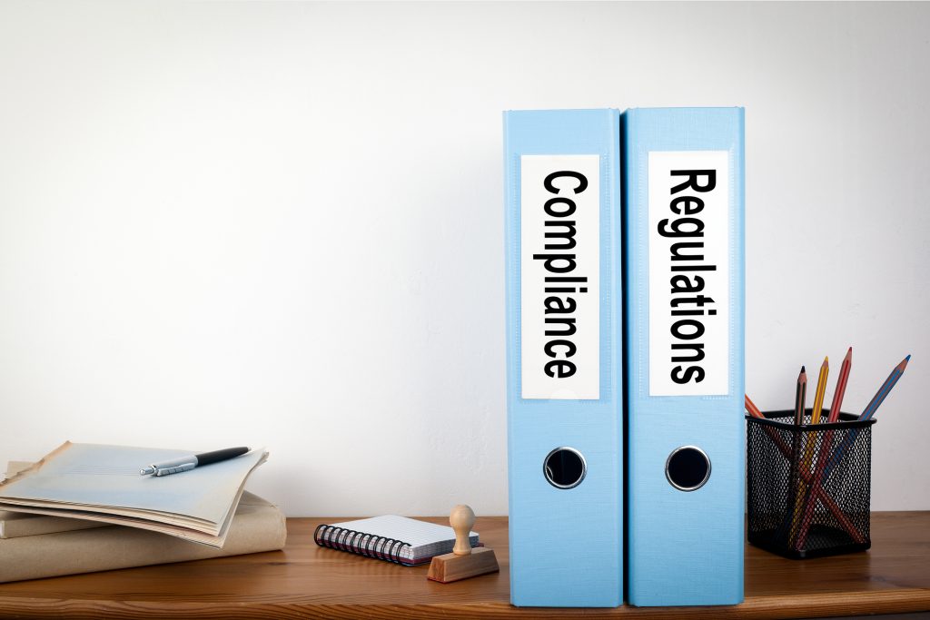 Compliance and Regulations binders in the office. Stationery on a wooden shelf