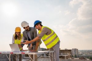 Diverse team of specialists with computer on construction site. Real estate building project with engineer, architect, business investor.